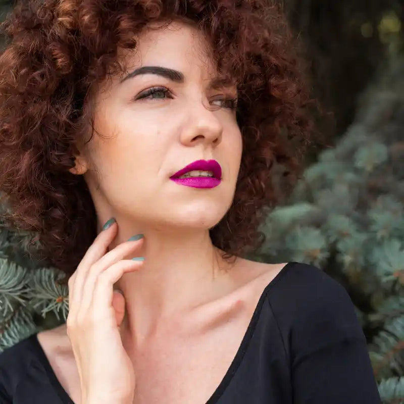Woman with curly red hair and bright pink lipstick.